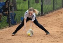 a woman reaching for a ball on a baseball field