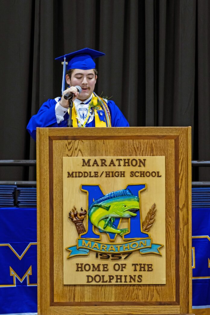 a man standing at a podium talking on a cell phone