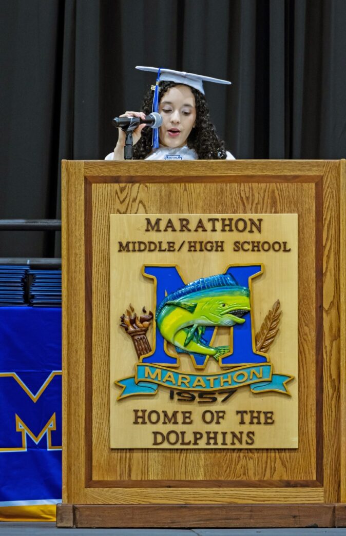 a woman standing at a podium in front of a microphone