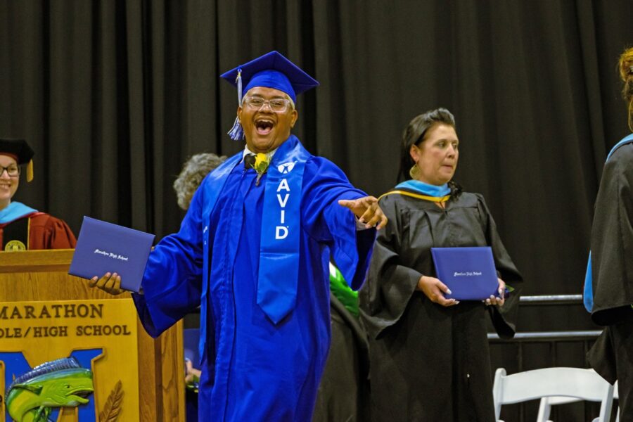 a man in a graduation cap and gown standing in front of a podium