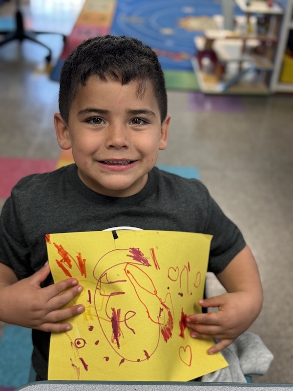 a young boy holding a yellow piece of paper