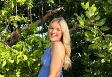 a woman in a blue dress standing in front of a tree