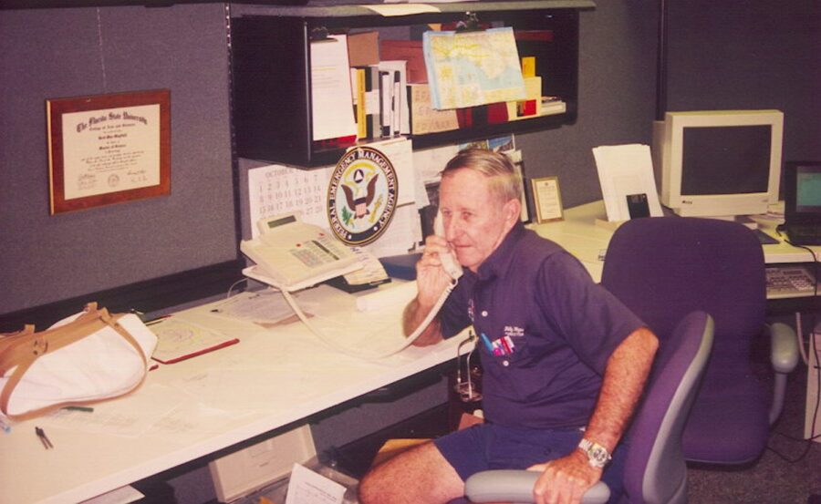 a man sitting at a desk talking on a phone