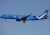a blue and white airplane flying in the sky