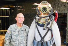 a man standing next to a statue of a man in a diving suit