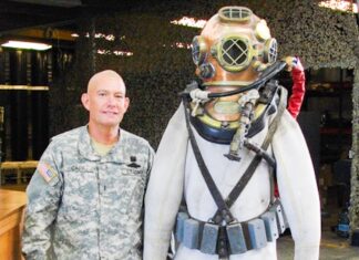 a man standing next to a statue of a man in a diving suit