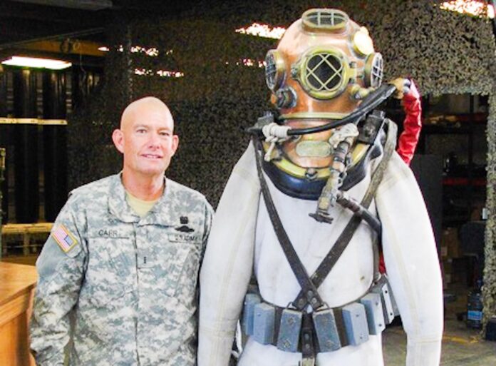 CARR mk v deep sea a man standing next to a statue of a man in a diving suit