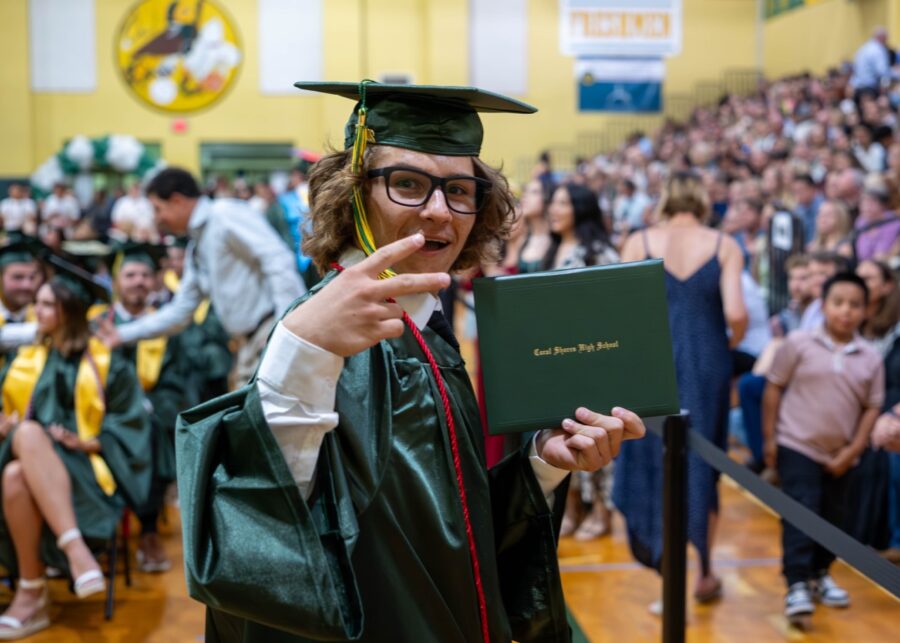 a man in a cap and gown points at a book