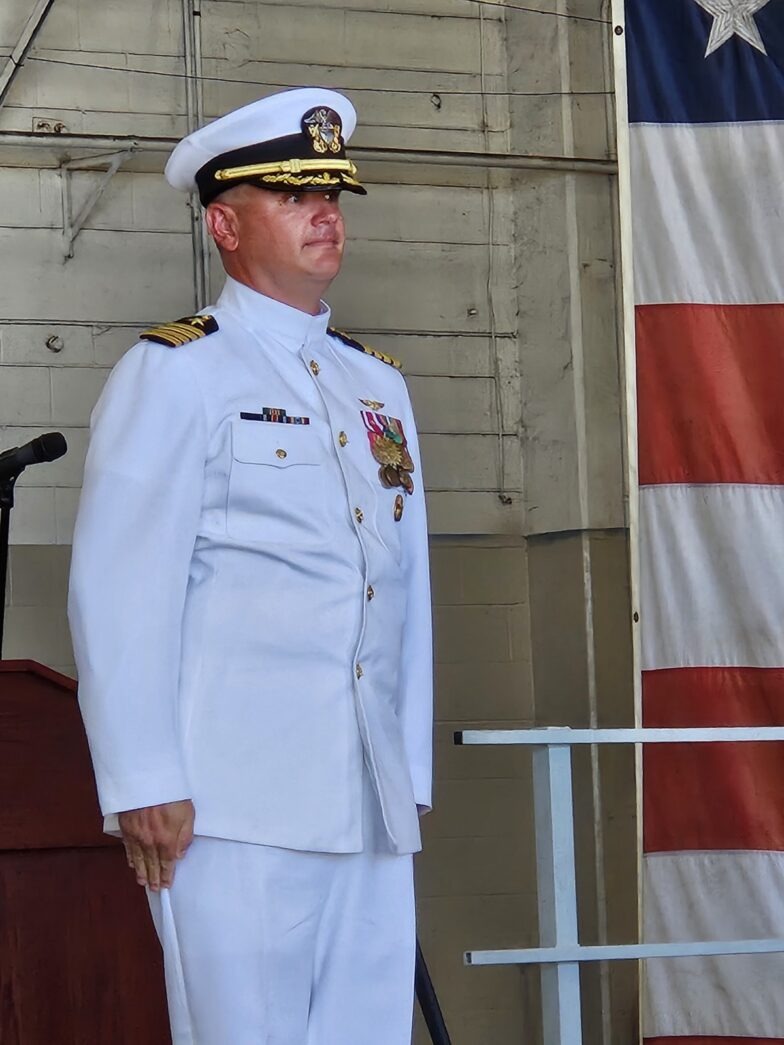 a man in a military uniform standing in front of a flag