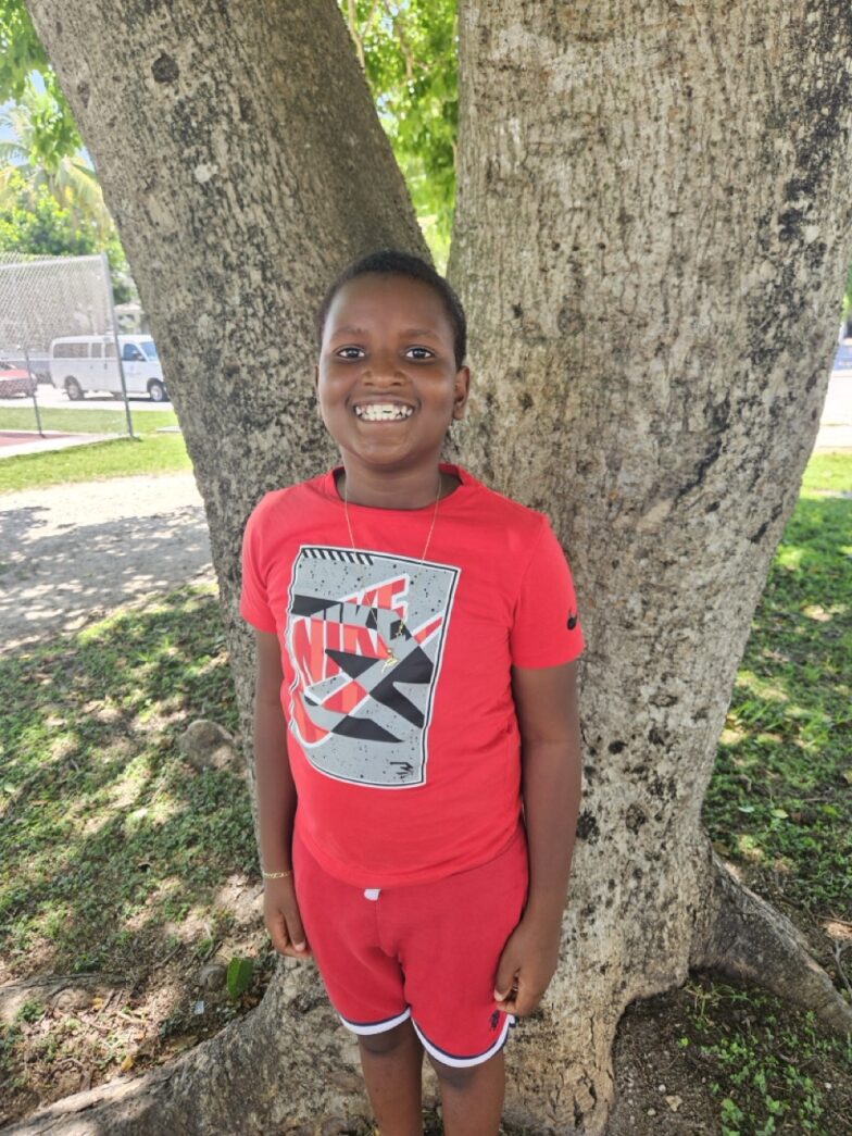 a young boy standing in front of a tree
