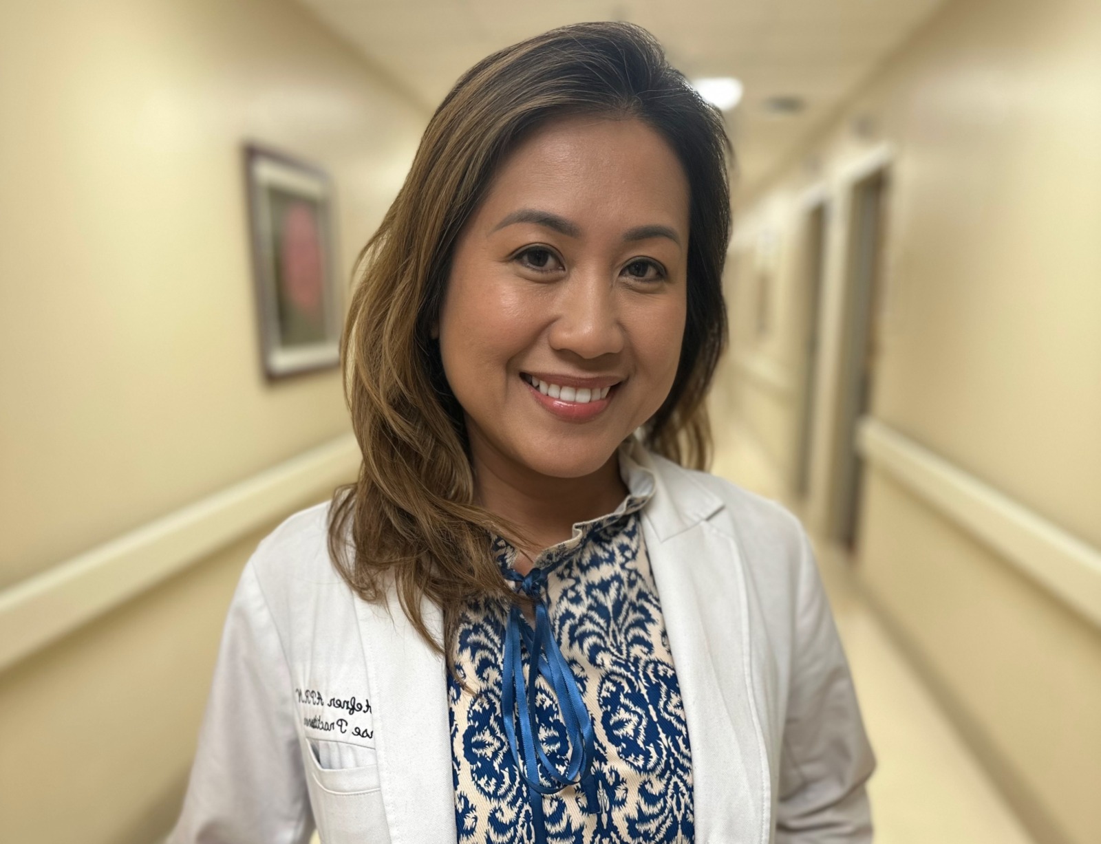 a woman standing in a hallway wearing a white coat and blue scarf