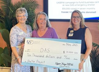 a group of women standing next to each other holding a large check