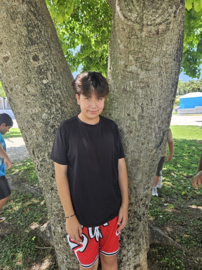 a young boy standing in front of a tree