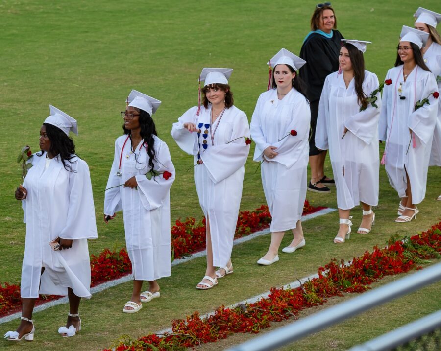 a group of women in white graduation gowns