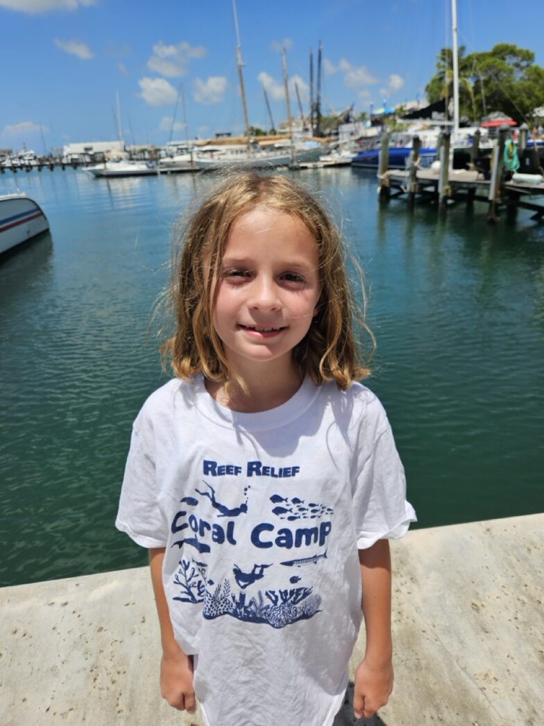 a little girl standing on a dock next to a body of water