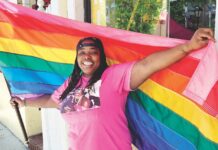 a woman in a pink shirt holding a rainbow flag
