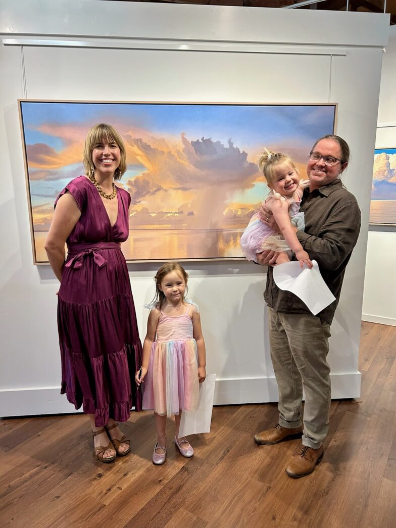 a man, woman and child standing in front of a painting