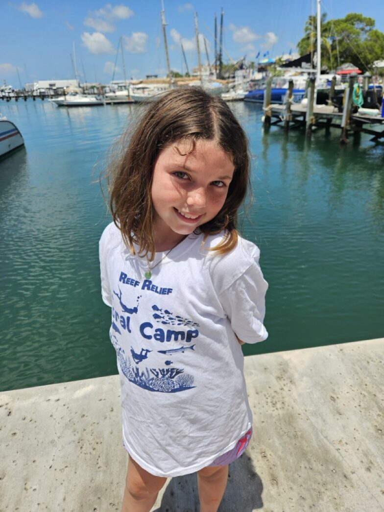 a little girl standing on a dock next to a body of water