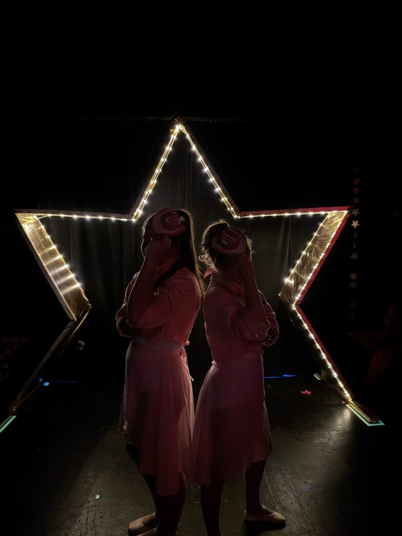 two women in pink dresses standing in front of a star