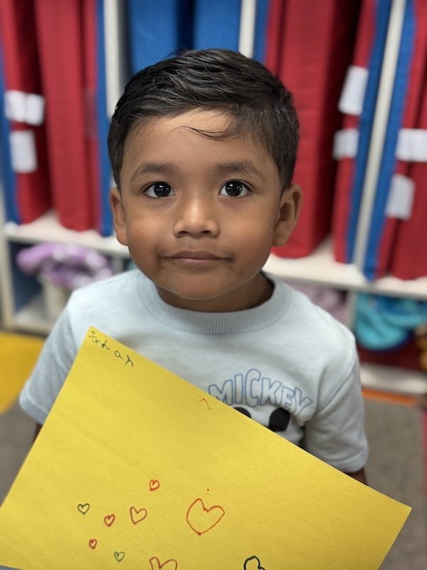 a young boy holding a yellow piece of paper
