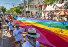 a group of people walking down a street holding a rainbow flag