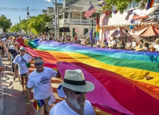 a group of people walking down a street holding a rainbow flag