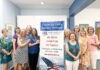 a group of women standing next to a sign