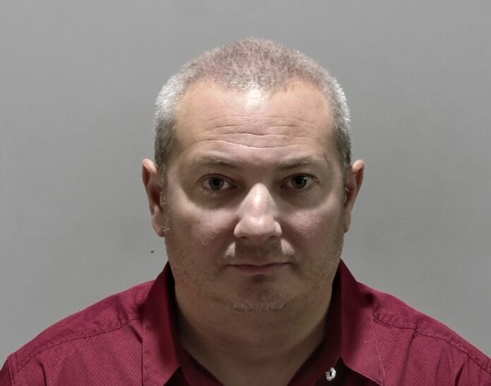 a man in a red shirt is looking at the camera