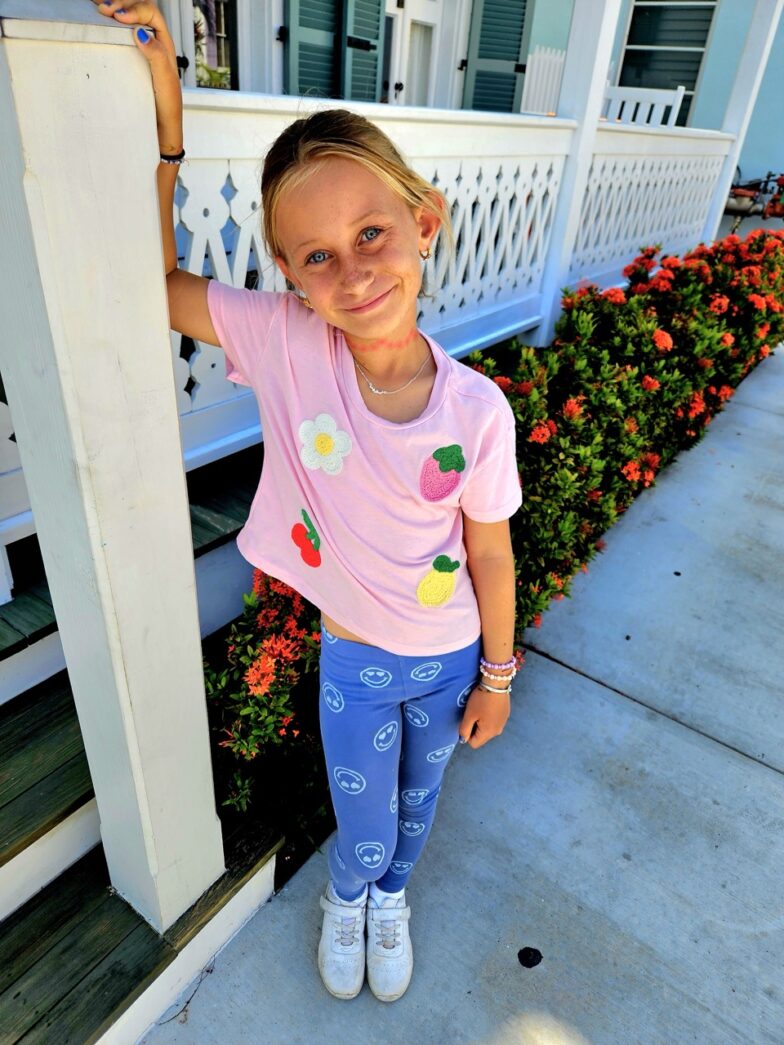 a little girl standing on the porch of a house