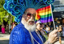 a man in a blue outfit holding a rainbow flag