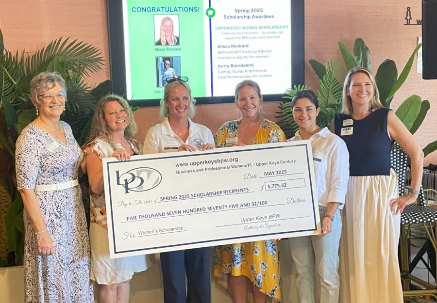 a group of women standing next to each other holding a large check