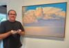 a man standing in front of a painting holding a controller