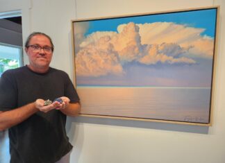a man standing in front of a painting holding a controller