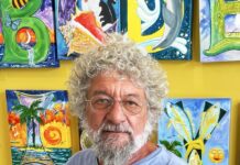 a man standing in front of a wall of paintings