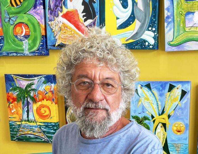 a man standing in front of a wall of paintings