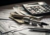 a calculator and a pen on top of a pile of papers