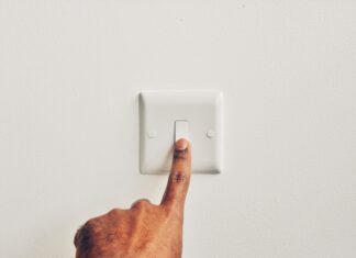 a hand pressing a light switch on a white wall