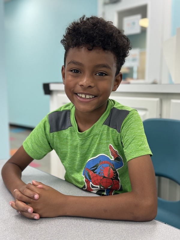 a young boy sitting at a table in a dental office