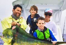 a group of people on a boat holding a fish