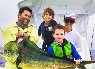 a group of people on a boat holding a fish