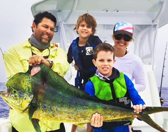 a group of people on a boat holding a fish