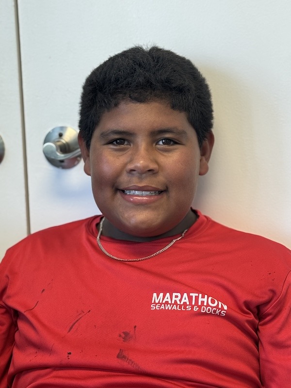 a young boy in a red shirt sitting in a chair