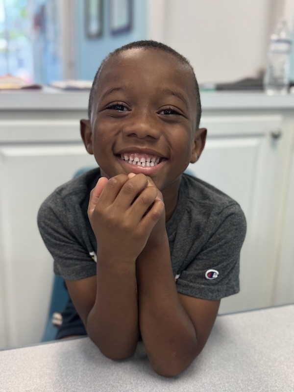 a young boy sitting at a table smiling