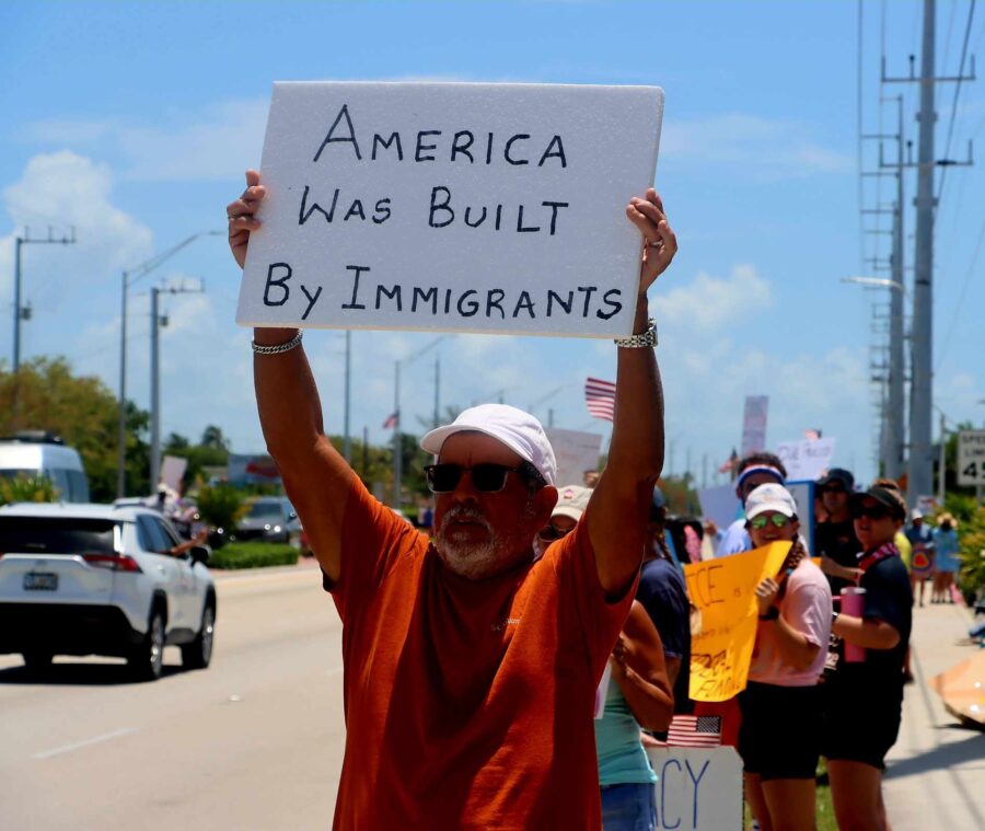 a man holding a sign that says america was built by immigrants