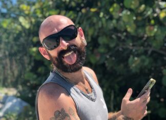 a man with a beard and sunglasses holding a cell phone
