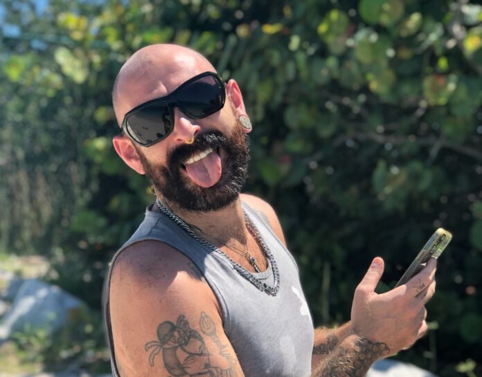a man with a beard and sunglasses holding a cell phone