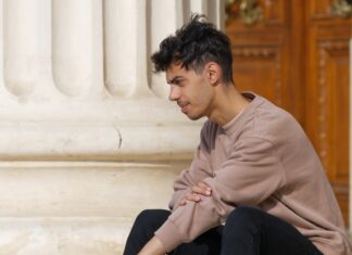 a man sitting on the ground next to a building