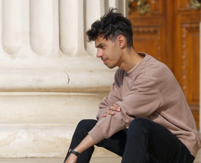 teenager a man sitting on the ground next to a building