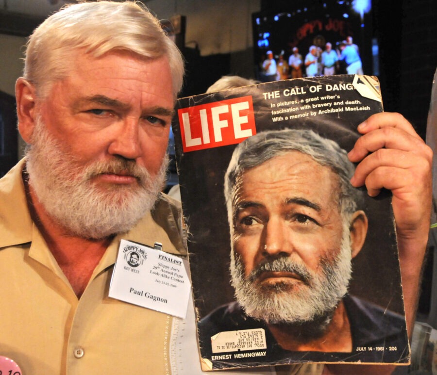 a man holding up a magazine with a picture of a man's face