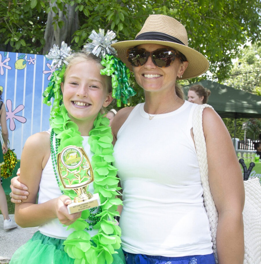 a woman standing next to a little girl wearing a hula skirt